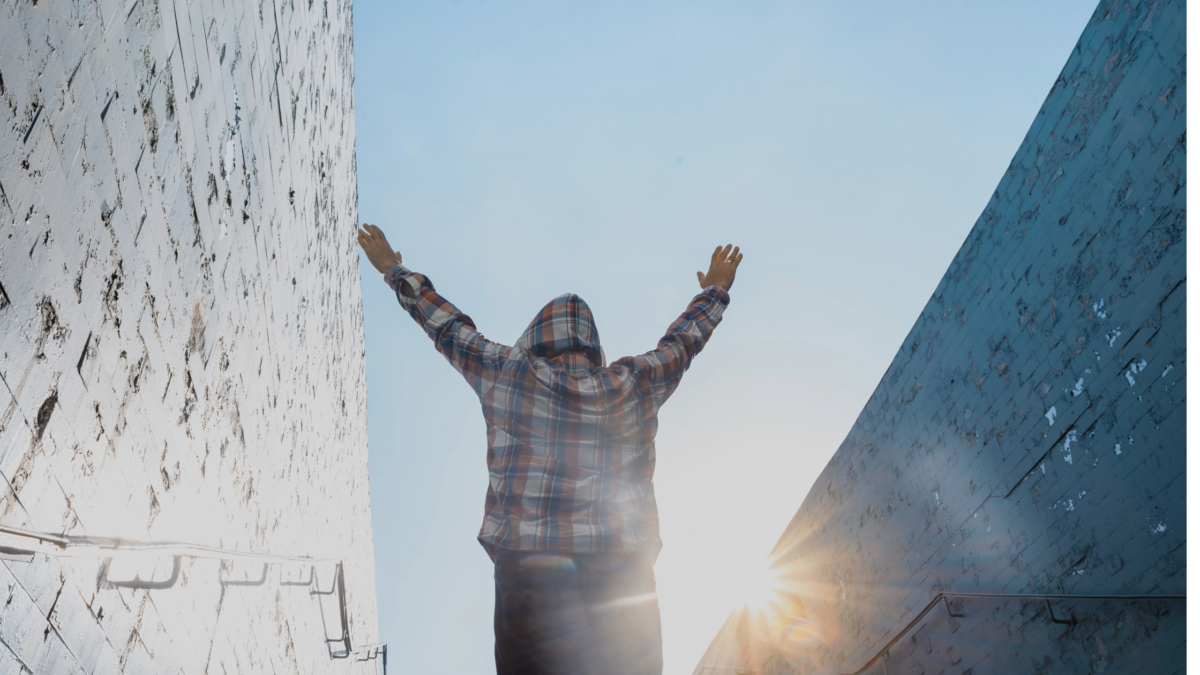 man with arms in air celebrating as sun goes down